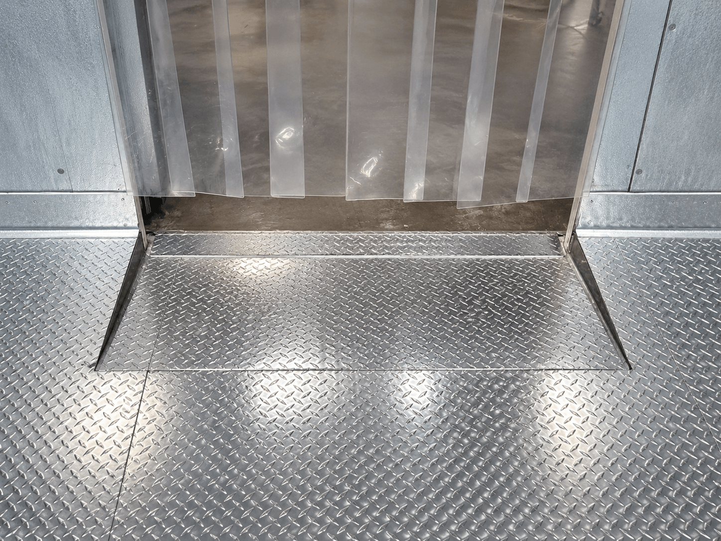 Diamond-plate drop-in ramp at a Coldrite walk-in entrance